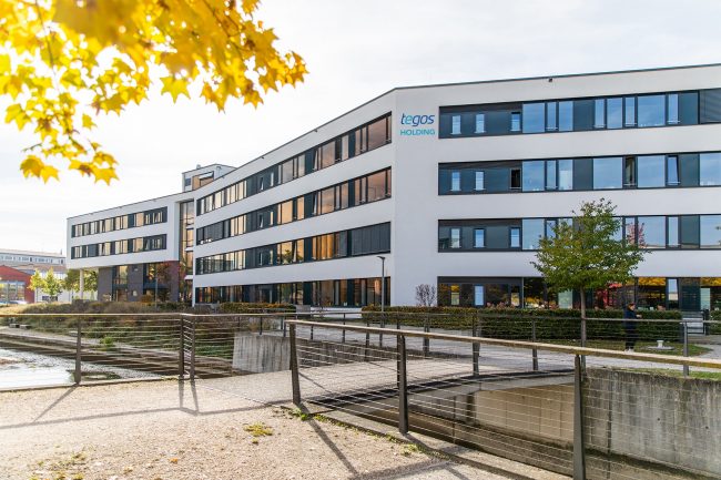 tegos-gebauede Gebäude der tegos Holding mit moderner Glasfassade in herbstlicher Umgebung.