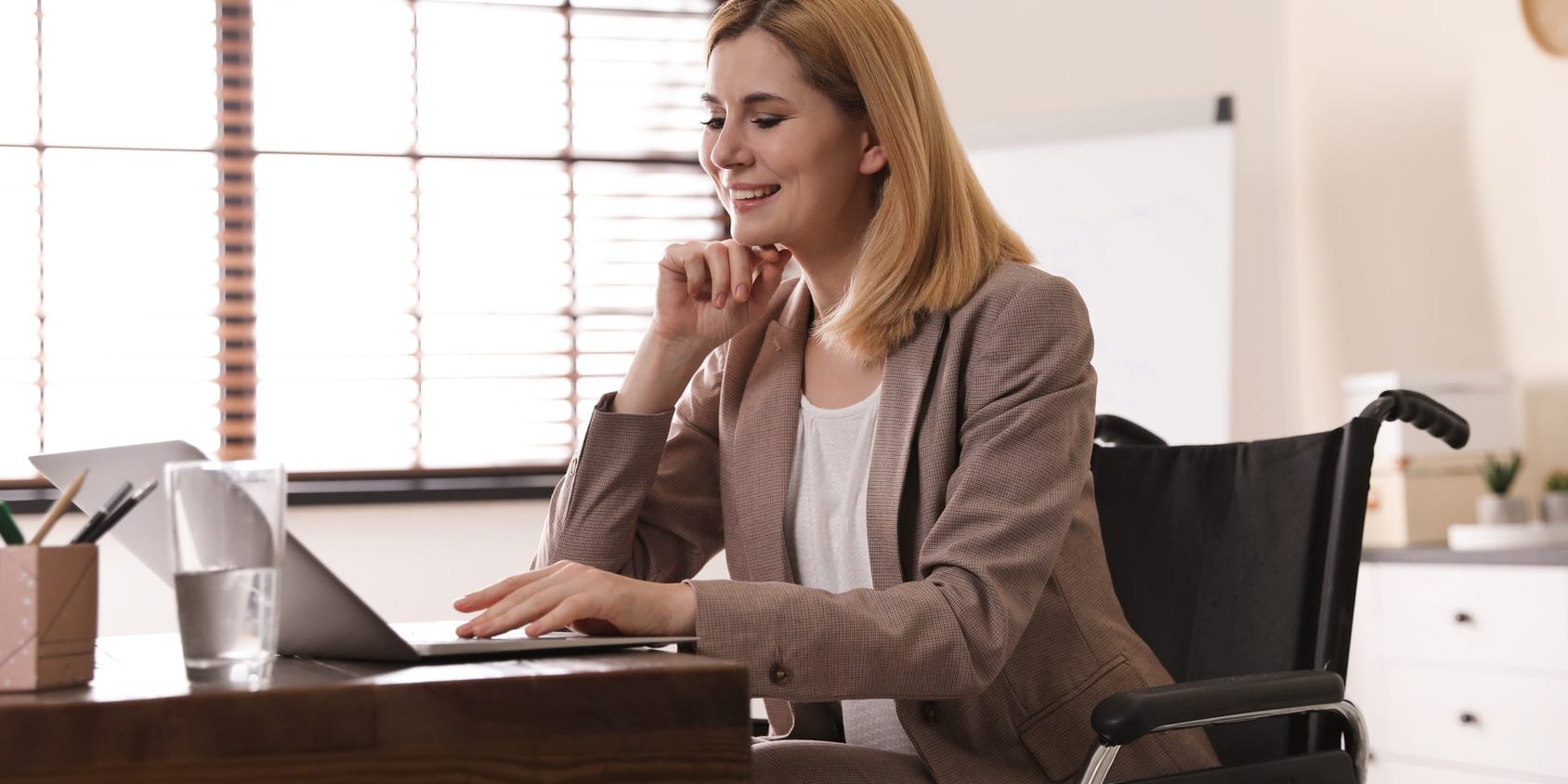 Portrait of woman in wheelchair working with laptop at table indoors sowis goes #makeITsocial