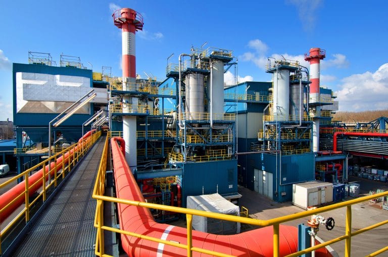 Industrielle Anlage der GSB mit Rohrleitungen, Schornsteinen und Wartungsgängen unter blauem Himmel.