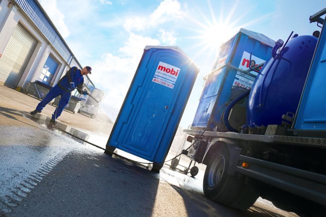 Reinigung einer mobilen mobi Toilette während die kräftige Sonne von hinten scheint.